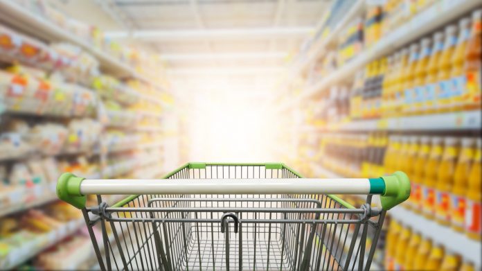 Supermarket aisle with empty green shopping cart